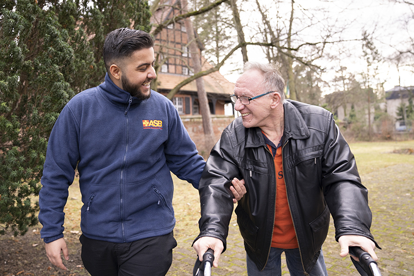Bundesfreiwilligendienst Eine junge ASB-Freiwillige pflanzt mit einem Mädchen Blumen an einem Gartenteich.